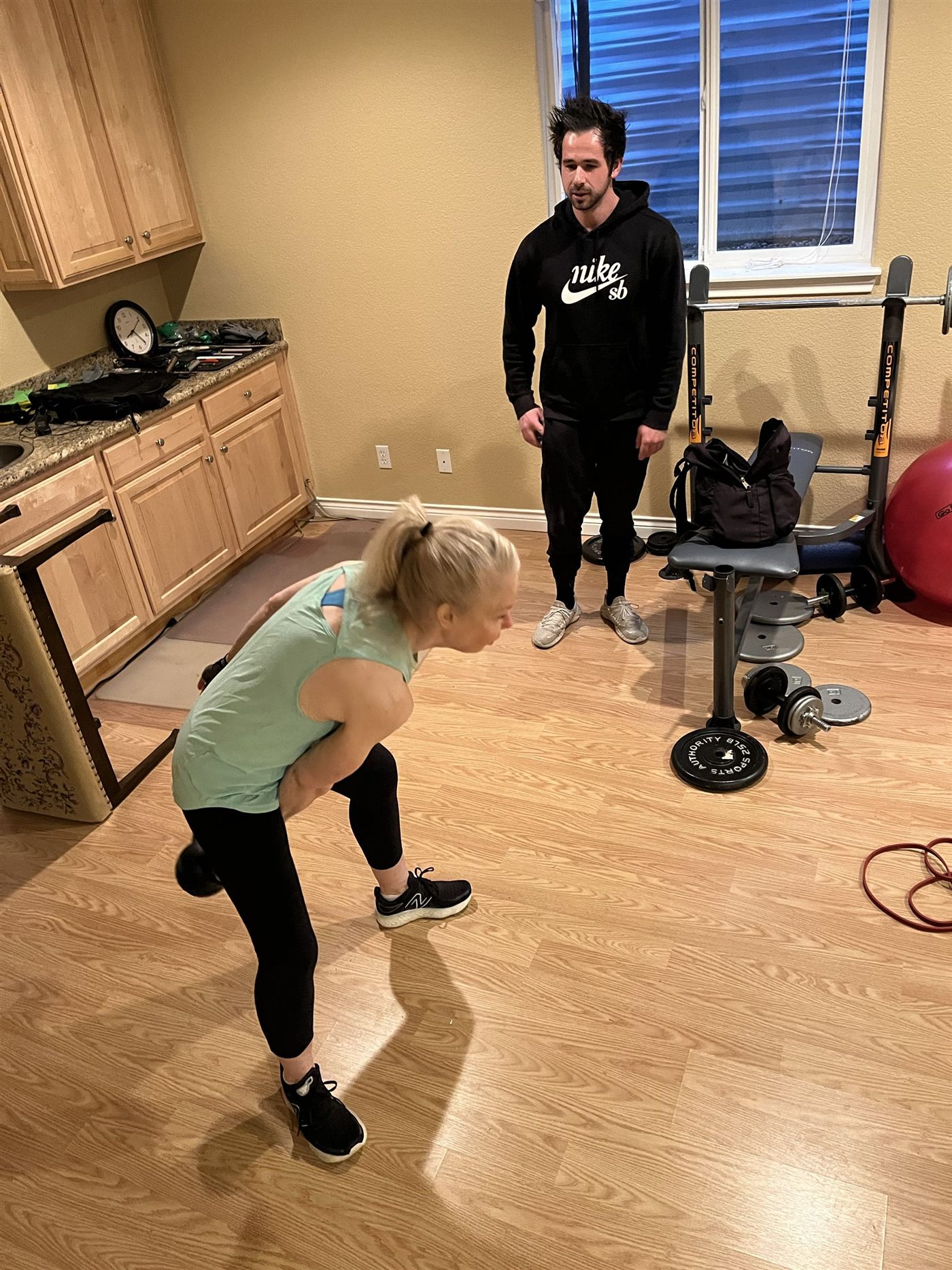 Justin coaching a client through a hinge movement in her home gym.